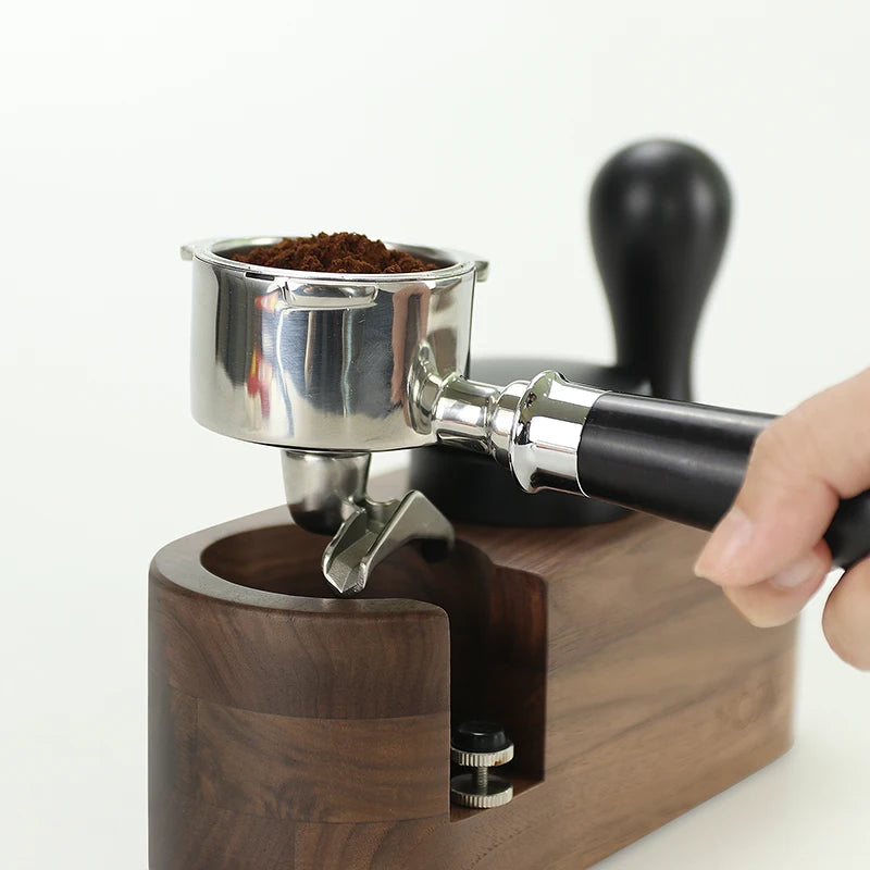 Hand holding a coffee grinder with a focus on the wooden base and metal components.